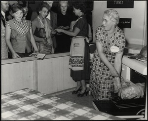 Eastern States Exposition. Mass. State Building. Mrs. Joseph Davis, demonstrating the proper way to roast a turkey while Mrs. Donald Sistare (Paxton, Mass.) passes out folders. This is at the Mass. Turkey Growers display.
