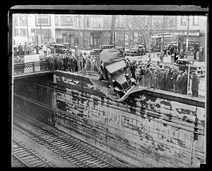 Spectators surround a truck which is half over the train tracks