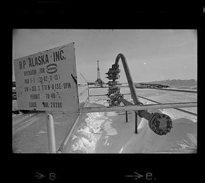 BP Alaska oil pipe, derrick in background, sign in foreground