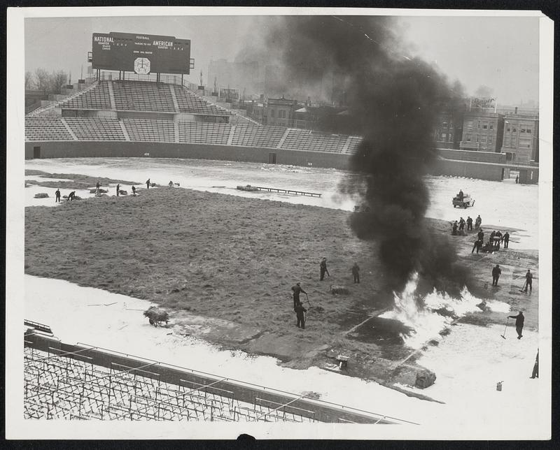 Thawing Out Wrigley Field For Championship Football Game. To insure proper playing conditions for the National Professional Football championship game between the Chicago Bears and the Washington Redskins this coming Sunday, workmen are sprayung gasoline on the field and then setting it a fire to melt the surface ice and soften the frozen playing sod to a depth of 6 inches. Hot blasts from an asphalt heater are also being used. Following this procedure a layre of straw and a tarpaulin was spread over the whole field.