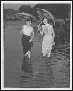 Many a Miss was trapped today by high water in rain-flooded streets. Here Beverly Mahoney (left) of Brainerd road, and Joan Dandrow of East Cottage street, Dorchester, get wet feet-plus as they cross Commonwealth avenue, Allston, on their way to work.