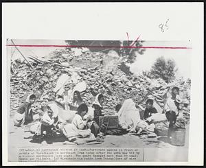 Earthquake Victims In Iran -- Survivors huddle in front of rubble at Moradtapeh in northeast Iran today after the area was hit by a violent earthquake last night. The quake damaged more than 50 small towns and villages.