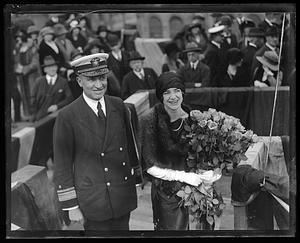 Unidentified woman holding a bouquet of flowers stands next to an admiral