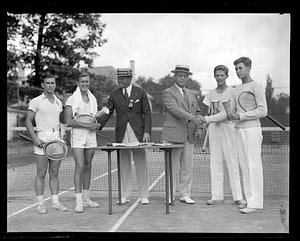 Four tennis players being presented with cups at a ceremony