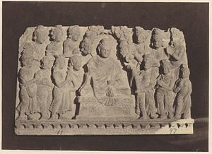 Stone carving of people gathered around a deity or religious figure