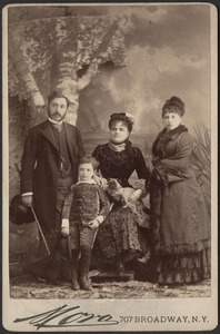 Photograph of three adults with a child and a dog