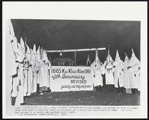 Klan Anniversary Rally-- Robed and masked Ku Klux Klansmen pose with sign announcing their anniversary at a rally and cross-burning here. The cross was burned in a nearby cow pasture last night.