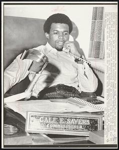 Chicago Bears running back Gale Sayers talks business on phone while on the job as Chicago Park District Commissioner 10/30. His crutch lies against the desk at left. Sayers is recuperating from an operation on his left knee for an injury suffered 10/11 in game with the Minnesota Vikings. Sayers is out of action for the rest of the season with the Bears, but with the Park District, that's something else again.