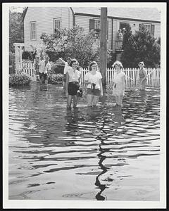 The Latest Thing in August fashion in Hyde Park is modeled by these flood-swept young women, from left, Joan Sullivan, Mary Walsh and Pat Lawrence. Bare feet and shorts are de rigeur on Belnel road.