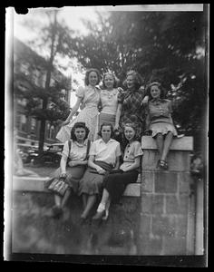 Seven women pose on a stone wall