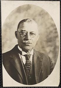 A man with a moustache, wearing glasses and a suit