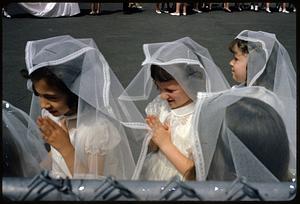 Girls wearing veils and holding their hands in prayer