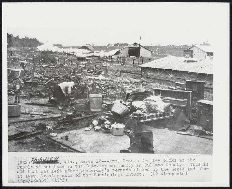 Mrs. George Crumley picks in the rubble of her home in the Fairview community in Cullman County. This is all that was left after yesterday's tornado picked up the house and blew it away, leaving much of the furnishings intact.