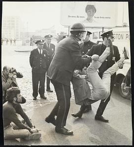 Boston Policemen left youth into patrol wagon at sit-in blockade outside Army Base. Story on Page 5.