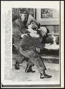 Flames of Dissent in Tokyo – A riot policeman, his back burning from an exploded firebomb, is helped by a fellow policeman during a clash with student demonstrators at a Tokyo railway station Sunday. The demonstrators were protesting Prime Minister Eisaku Sato’s visit to the United States this week. Sato leaves for Washington Monday for talks with President Nixon, including discussions on the return of Okinawa to Japan.