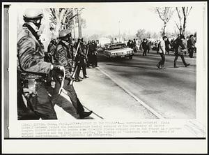 Caught in the Middle -- A surprised motorist finds himself between police and demonstrators Monday morning on the University of Denver campus. Police moved in to remove some 800-1000 youths comping out on the campus in a protest against Cambodia and the Kent State deaths. The closing of "Woodstock West" was devoid of violent confrontation.