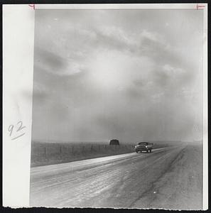 Dust Against the Sun--A dust storm typical of the blows kicking up the dry soil of Colorado plains, dims the midafternoon sun in this photo made east of Denver. A motorist traveling U.S. Highway 36 flicks on his lights because of dusty shadows. This first general dust storm of the year spread from southern Nebraska through parts of Colorado, Kansas, Oklahoma, New Mexico and Texas.