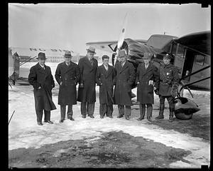 A group of men standing in the snow in front of airplanes