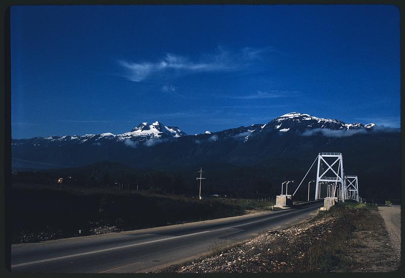 Road and Revelstoke Suspension Bridge with hills and mountains in