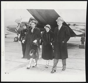 Acheson Returns for UN Meeting--Accompanied by his wife and Mrs. Lester B. Pearson (center), Secretary of State Acheson leaves presidential plane at La Guardia Field after flight from Ottawa to attent special UN session today on India's proposals to end Korean war.
