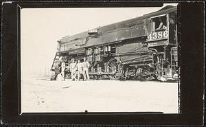 Soldiers stand next to a railroad locomotive "4386"