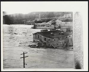 Floodwater Hides Falls--The Oregon City Falls (at left center) are nearly obliterated from view by raging floodwaters of the swollen, rising Willamette River. The Crown Zellerbach paper mill in the background was closed by the flood. Water reached the top of tis third-floor windows. The Publishers Paper Co. plant in the foreground also was flooded and closed.