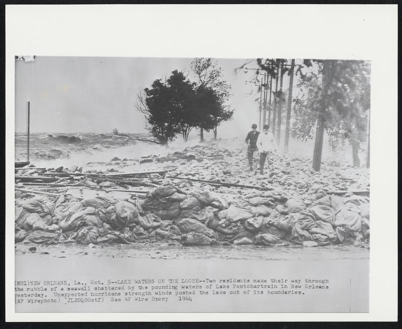 Lake Waters on the Loose-- Two residents make their way through the rubble of a seawall shattered by the pounding waters of Lake Pontchartrain in New Orleans yesterday. Unexpected hurricane strength winds pushed the lake out of its boundaries.