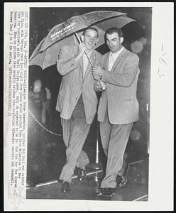 Battery Water--Milwaukee Brave teammates, pitcher Bob Buhl and catcher Del Rice, walk through rain last night from plane which carried them from Milwaukee to New York for tomorrow's sixth World Series game. Buhl is expected to be in the box for the Braves tomorrow. When he pitches Rice usually catches him--replacing Milwaukee captain Del Crandall. Braves lead 3 to 2 in series.