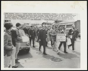 Clergy March With Police Protection - Youths watch from sidelines as a group of clergymen and pacifists march through South Boston today on way to demonstration on Boston Common. Clergymen said they were asserting right to dissent "as the cornerstone of American Democracy." They also protested what they said was lack of police protection last week when South Boston youths beat up draft card burners. Today 150 police guarded marchers.