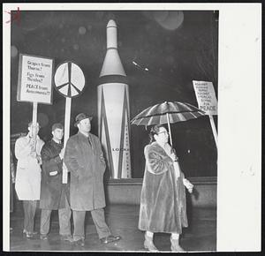 Sign-Carrying pickets march in rain past model of Navy's Polaris Missile outside of Franklin Institute in Philadelphia. Vice Adm. William F. Raborn, chief of Navy ballistic missile program, was speaker inside. Pickets were members of Youth for Nuclear Disarmament group protesting our nuclear buildup.