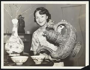 Made in Tibet more than 300 years ago and presented to the ruling Prince of Kashmere, India, by Dalai Lama, Chinese priest. The brass-covered wooden jug was brought to San Francisco's Chinatown by a Britisher many years ago. Miss Mee Lan Lee, San Francisco Chinese girl, is pouring old wine into older porcelain from the Yung Ching dynasty.
