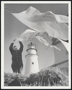 A Stiffening Breeze billows out Mrs. Ray Benway's wash. Each of the three couples now on island enjoy a 48-hour pass to the mainland every three weeks.
