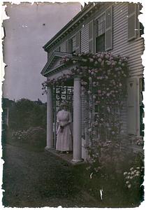 "White Gate" with woman standing on porch
