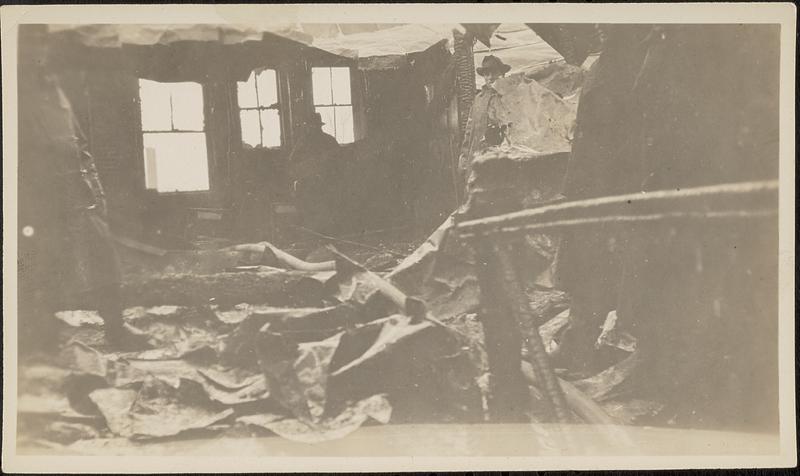 Interior of burned building after fire, with firemen present