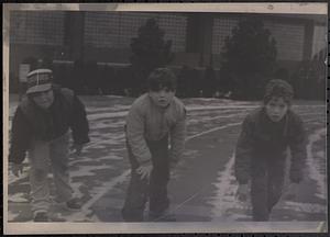Three boys on a track getting ready to race