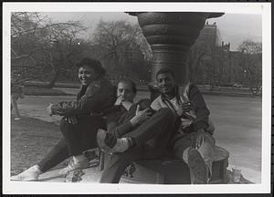 Three young people sitting on the base of the Japanese Lantern sculpture in the Boston Public Garden