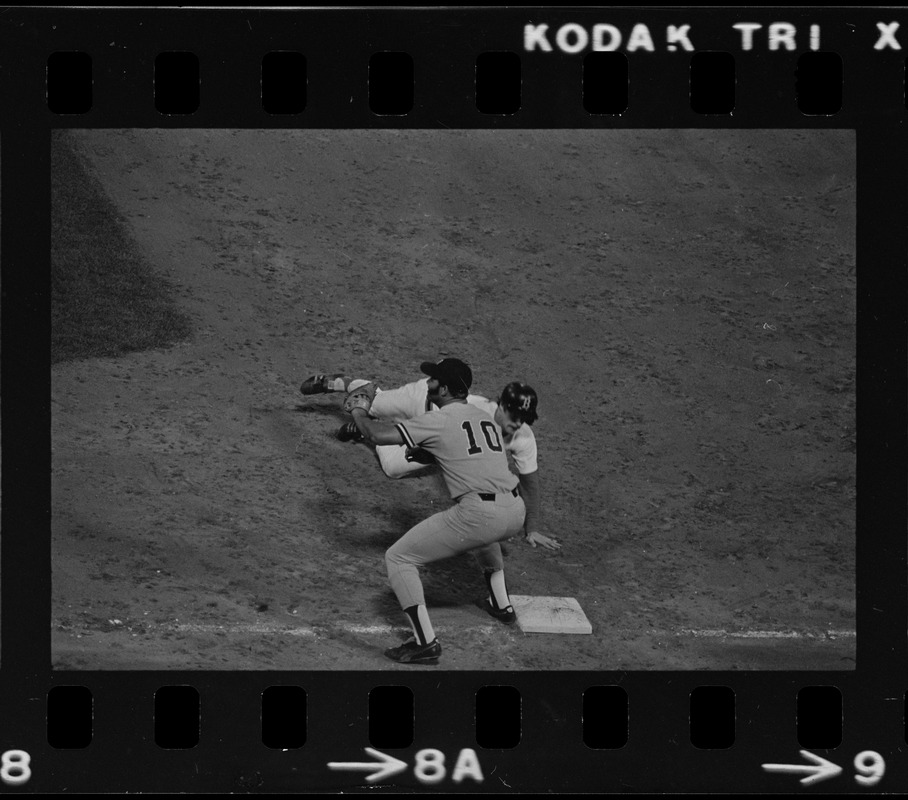 New York Yankees first baseman Chris Chambliss (#10) awaits an attempted pick-off throw, while Red Sox base runner Rick Burleson (#7) slides back towards first base