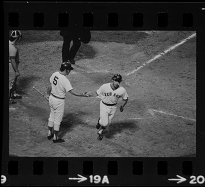 Unknown Boston Red Sox player (#5) congratulates unknown teammate crossing home plate following home run