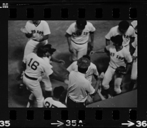 Boston Red Sox first baseman Carl Yastrzemski (holding first-base glove in his left hand) and a group of other Red Sox players including outfielder Rick Miller (#16) and pitching coach Lee Stange (#35) grouped around the first base dugout at Fenway Park as a stadium usher applauds