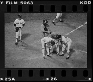 Red Sox batter Rick Burleson (#7) is attended to at home plate (after being hit with a pitch by Texas Rangers pitcher Doc Medich in the bottom of the 7th inning) by the Red Sox team trainer and Red Sox manager Don Zimmer as Texas Rangers catcher Jim Sundberg (#10) and unknown Red Sox batboy look on