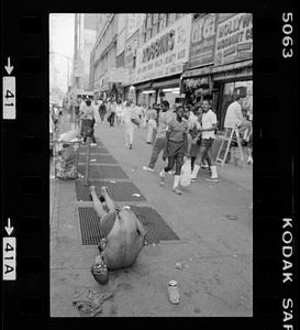 A man on the ground of a busy sidewalk