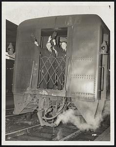 All Aboard for Nashua- Flagman Joseph Gendron, left, and T.G. Coughlin, assistant conductor, wave a farewell as a Nashua-bound train pulled out of North Station last night following announcement of a five-day truce that forestalled the scheduled railroad strike after a brief delay.