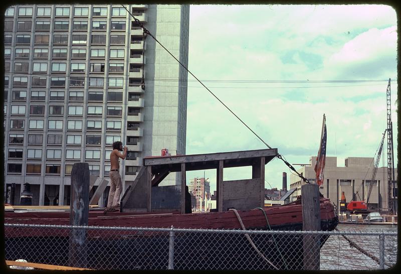 A man on a docked boat drinking from a can