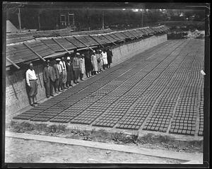 A group of people standing in front of bricks laid out on the ground