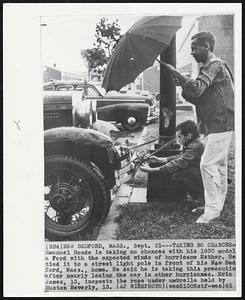 Taking No Chances -- Emanuel Bonde is taking no chances with his 1930 model A Ford with the expected winds of Hurricane Esther. He tied it to a street light pole in front of his New Bedford, Mass., home. He said he is taking this precaution after nearly losing the car in other hurricanes. Eric James, 13, inspects the rope under umbrella held by Huston Beverly, 13.