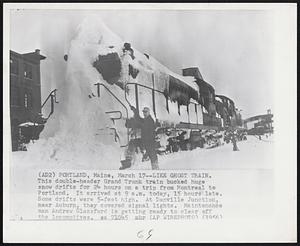 Portland, Maine - Like Ghost Train. This double-header Grand Trunk train bucked huge snow drifts for 24 hours on a trip from Montreal to Portland. It arrived at 9 a.m. today, 15 hours late. Some drifts were 5-feet high. At Danville Junction, near Auburn, they covered signal lights. Maintenance man Andrew Glassford is getting ready to clear off the locomotives.