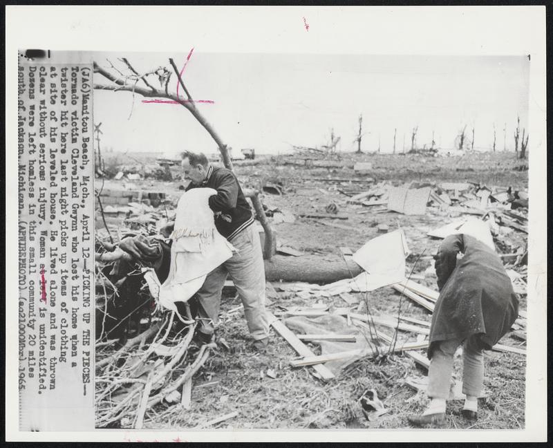 Manitou Beach, Mich. – Picking Up The Pieces – Tornado victim Cleveland Gwynn who lost his home when a twister hit here last night picks up items of clothing at site of his leveled house. He lived alone and was thrown clear without serious injury. Woman is unidentified. Dozens were left homeless in this small community 20 miles south of Jackson. Michigan.