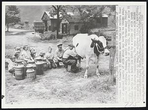 Bossie's Not on Strike--Nine of Dairyman Fred Hohman's 11 children watch their Dad relieve Bossie of several quarts of milk which may have to be thrown away. Despite 11 children, Hohman, a small diary farmer near Pittsburgh, has trouble getting rid of the milk. He normally sells 55 gallons daily to a dairy now idled by a strike of milk truck drivers in Western Pennsylvania. The cans contain milk which Hohman might be forced to dump. The children (l. to r.) are: Bobby, 8; Blanche, 12; Kitty, 16; Clara, 13; Mary, 15; Margaret, 9; Myrtle, 9; Frank, 10; and Bill, 20.
