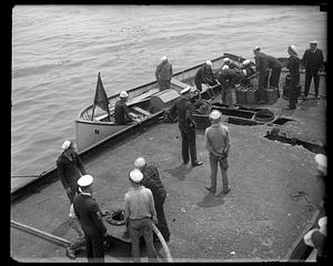 Sailors standing in and by a boat, "M"