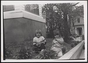Two children sitting in a garden bed